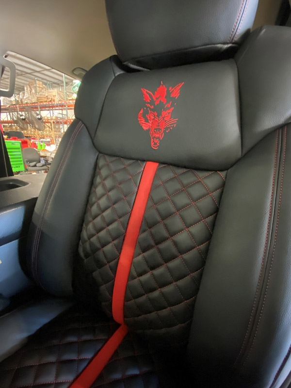 Black truck seat with red stitching and logo